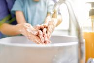 Kinderhände, die gemeinsam mit denen eines Erwachsenen gewaschen werden